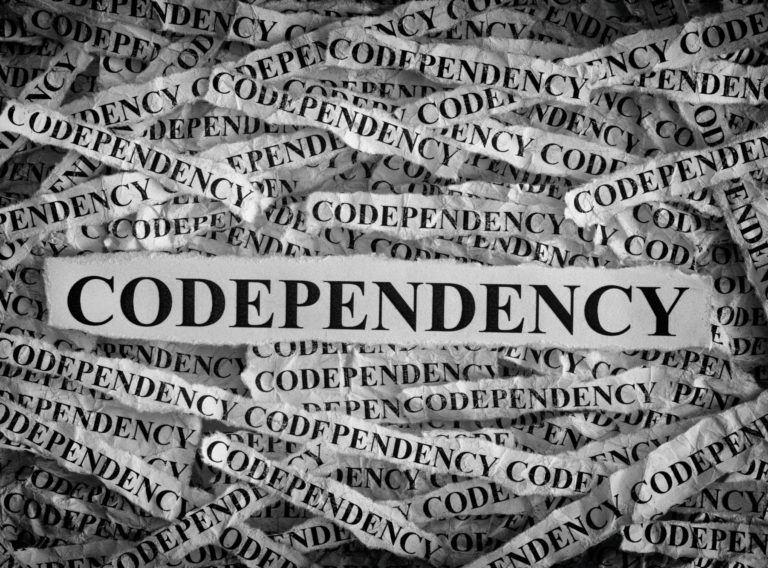 Codependency. Torn pieces of paper with the words Codependency. Concept Image. Black and White. Closeup.